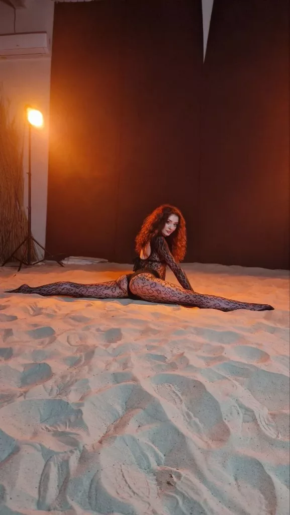 Submissive camgirl Metaxa in stockings, leaning back with playful smirk