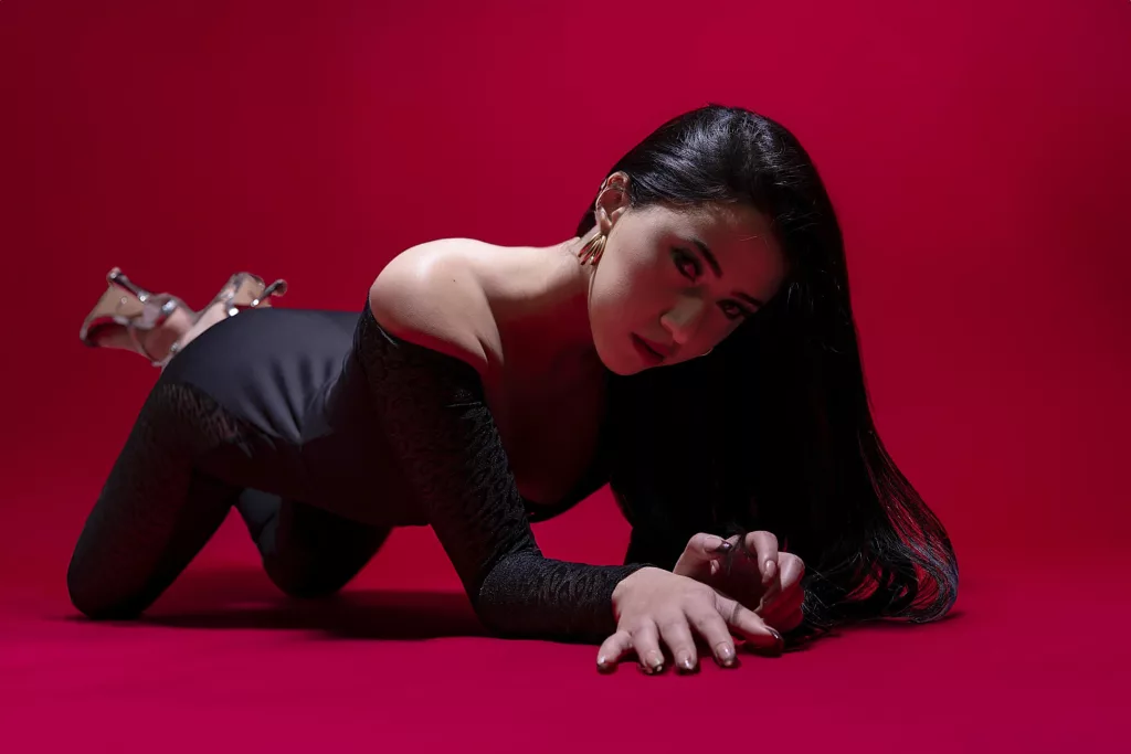 SamyCruzz is dress in a all black showing of set in a full red background