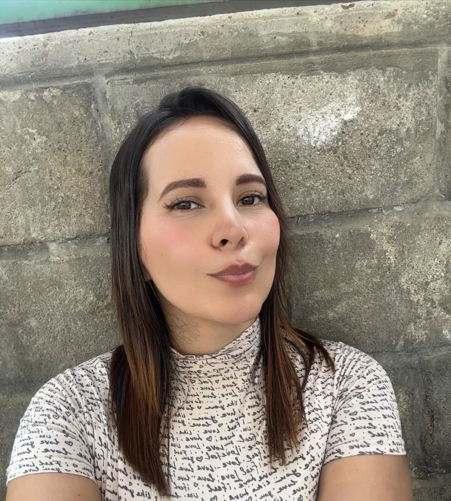 SaritaVelez shows off her sweet smile as she stands behind a stone wall