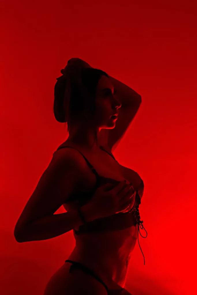 AprillRosen is in a studio shoot with a red back light, she is wearing only a bra and panty set.