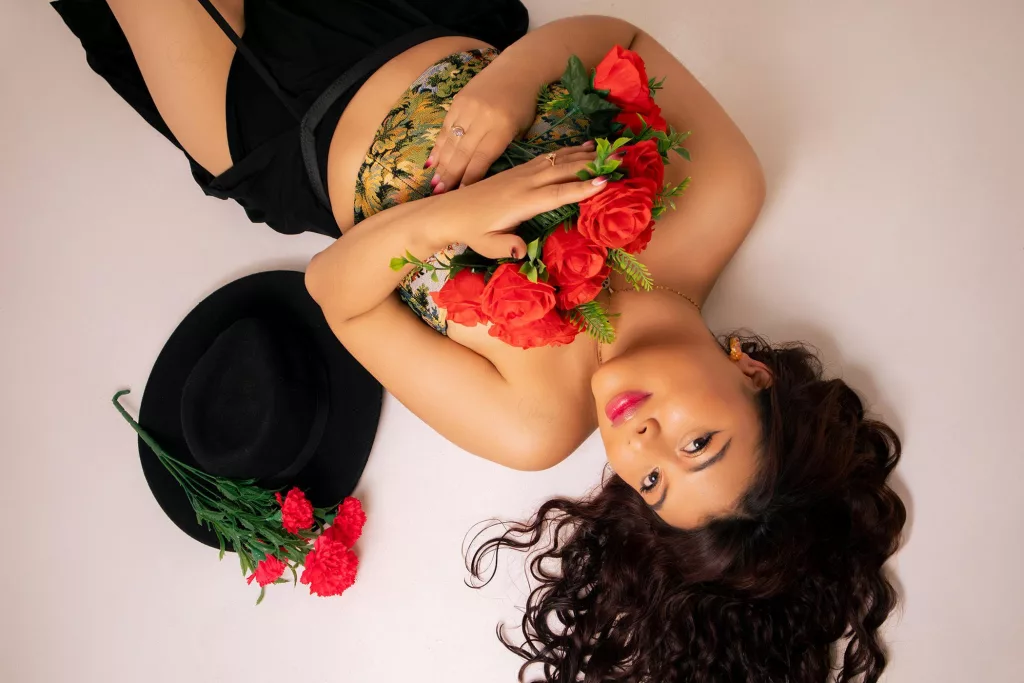 NoemiThornee lays on her back holding flower as a thick Latina Asian