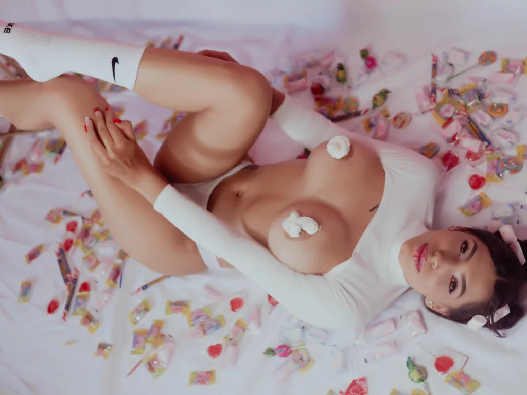 On her back, huge tits exposed, Yeline arches in submissive surrender.