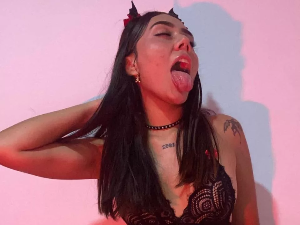 AlannaJonson on couch, black lace, red lips, dark hair, dim.