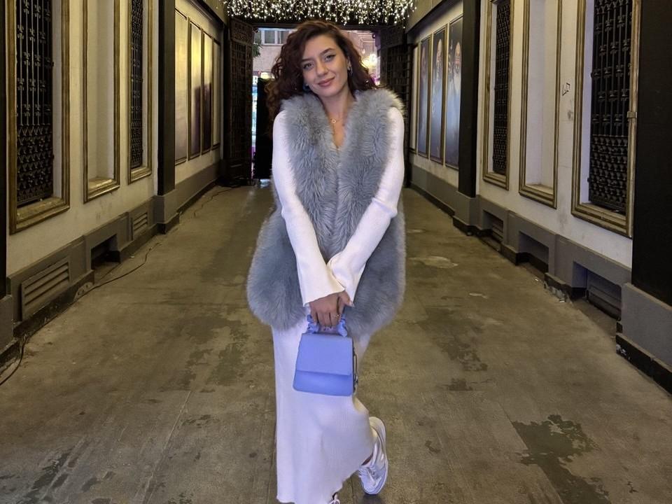 BubbleHeat in white dress, fur vest, holding blue purse