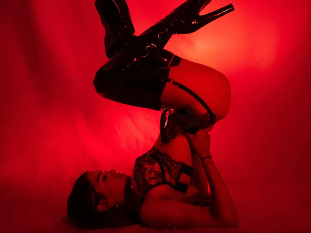 VanelopeRusso in red latex, riding crop, bent over bed, intense pose