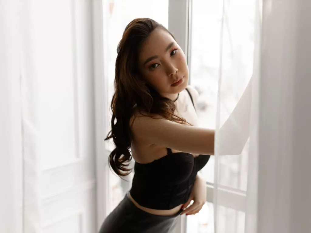 AnnaReyla in black strapless top by sunlit window—nude men small penis fantasies begin here.