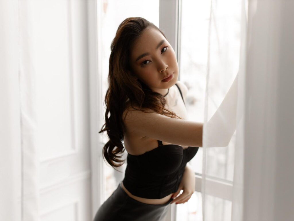 AnnaReyla in black strapless top by sunlit window—nude men small penis fantasies begin here.