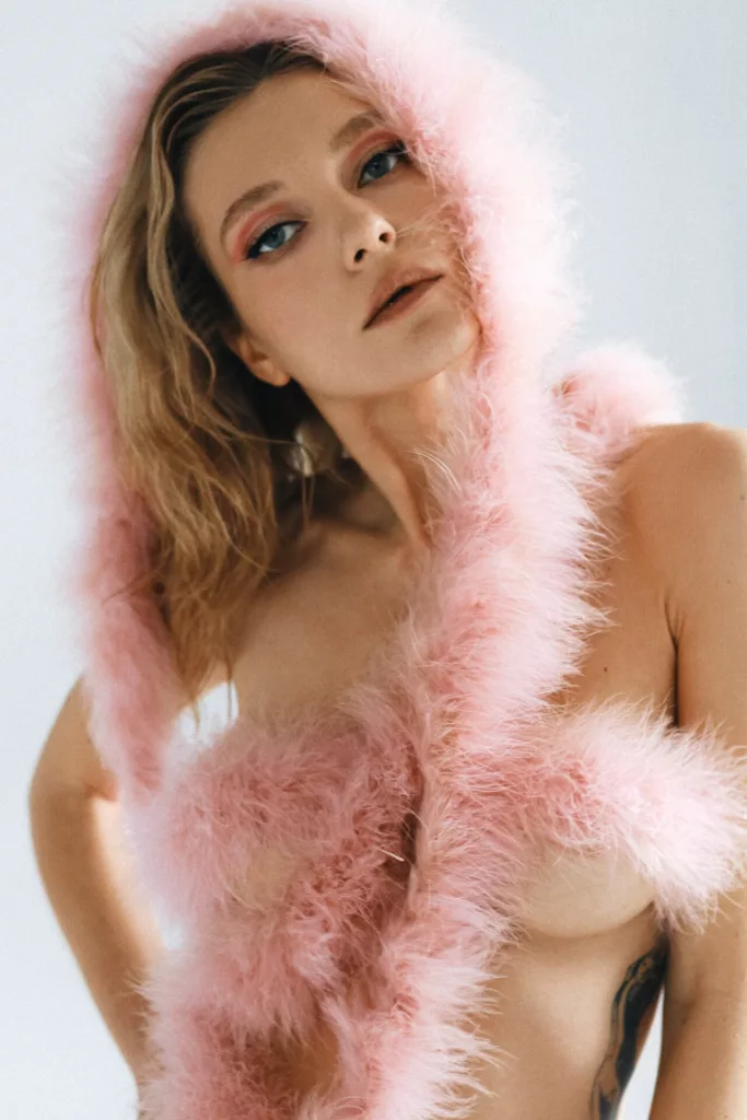 EolantaMarina topless, pink feather boa, blue eyes, lips parted, sensual gaze.