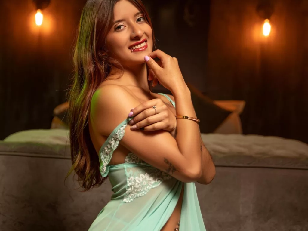 Voyeur neighbor’s dream: XimeRocks in green lace, smiling, warm lights, cozy backdrop.