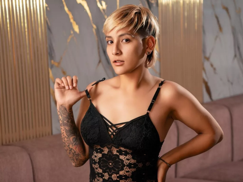 DannyRouds: nude tomboy in black lace dress, tattooed arm, gold-accented walls