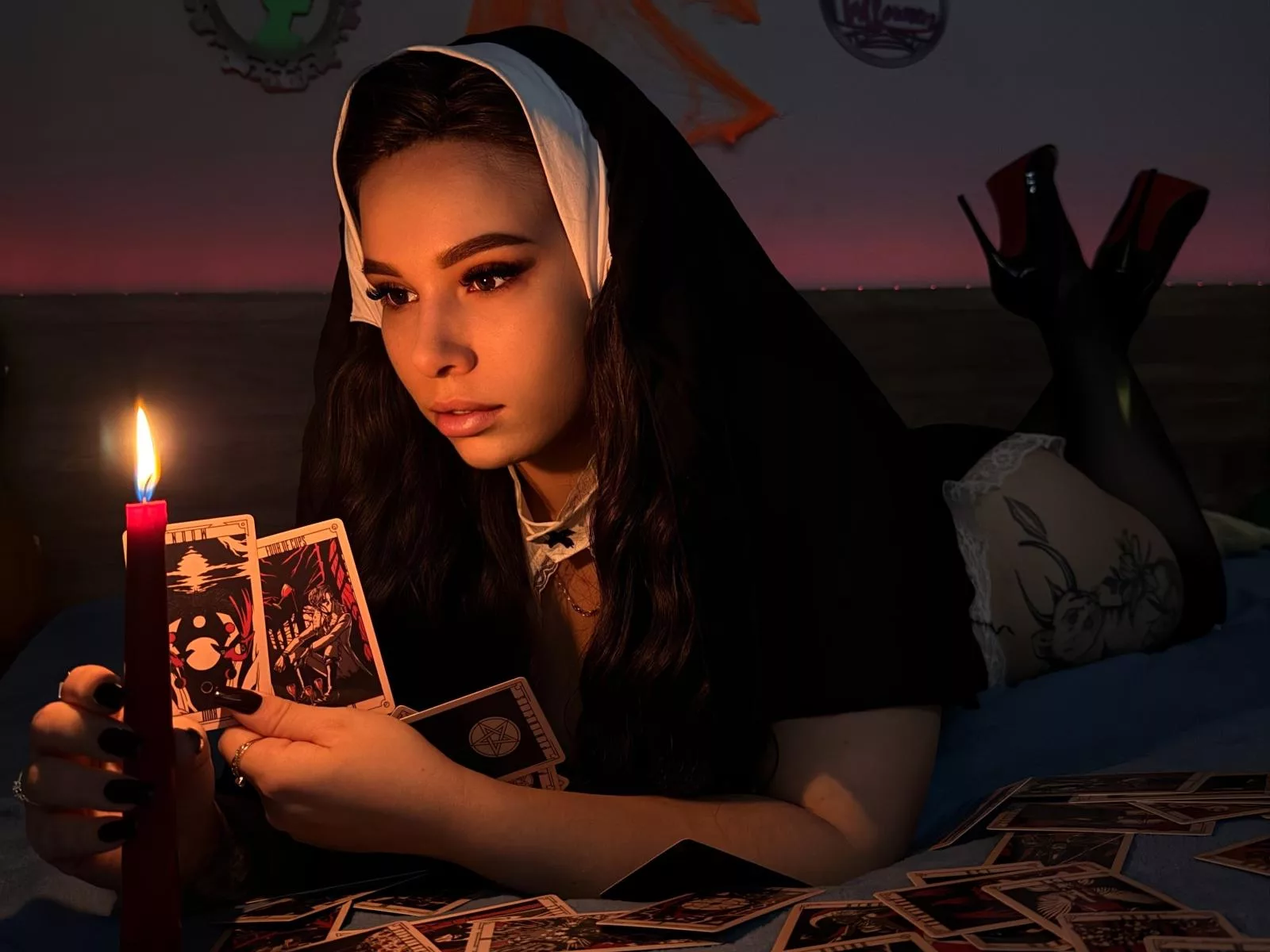 Niferttiti dressed as a nun reading tarot cards by candlelight.