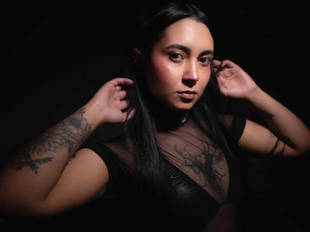 Close-up of tattooed GabyMathew in black attire for a naked run aesthetic.
