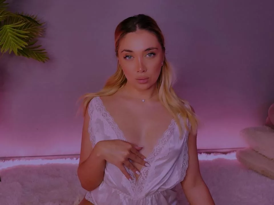 JessicaClarks in white lingerie, posing on a fluffy bed, ready for a private chat challenge.