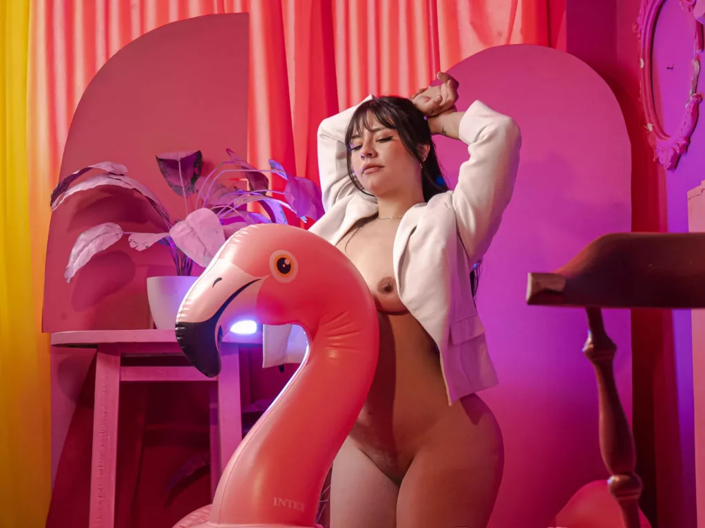 Thick Latina Sexy RoseAnna in a white blazer and pink background.